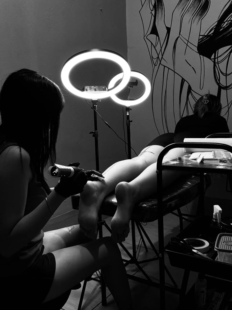 Sessão de tatuagem iluminada por duas luminárias